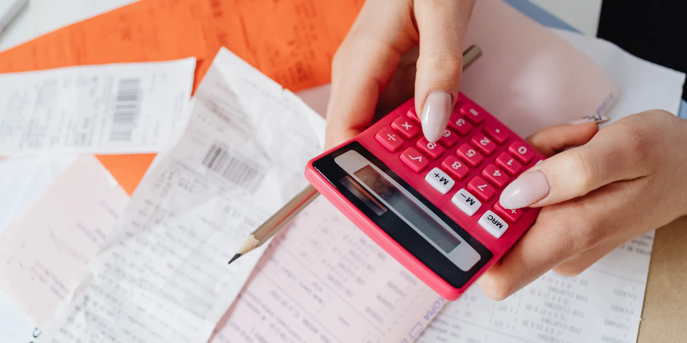 Hands using a calculator over printed receipts